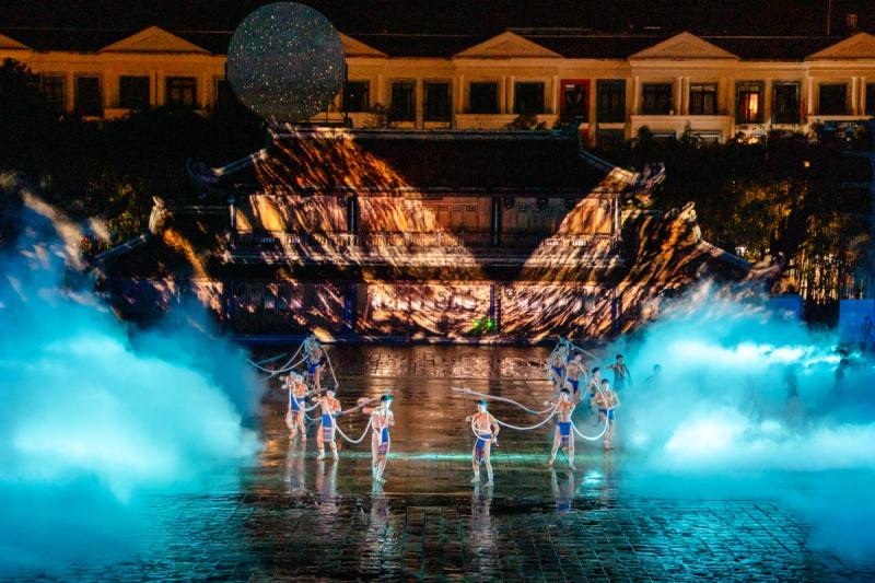 Performers surrounded by blue-lit stage mist