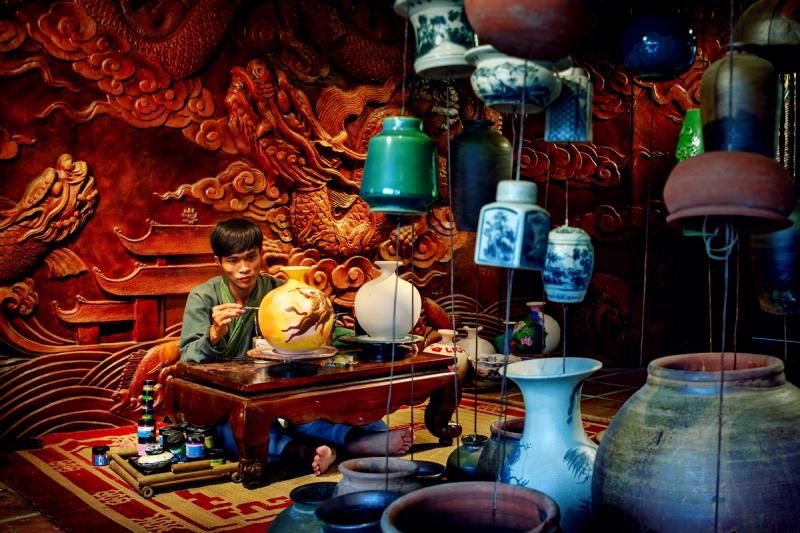 A craftsperson working beside decorated ceramic objects