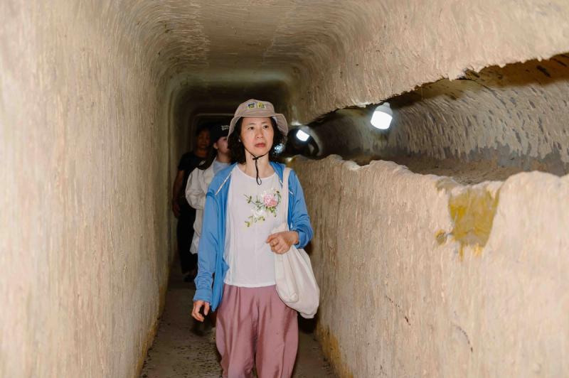 Visitors inside a narrow illuminated tunnel at the prison site