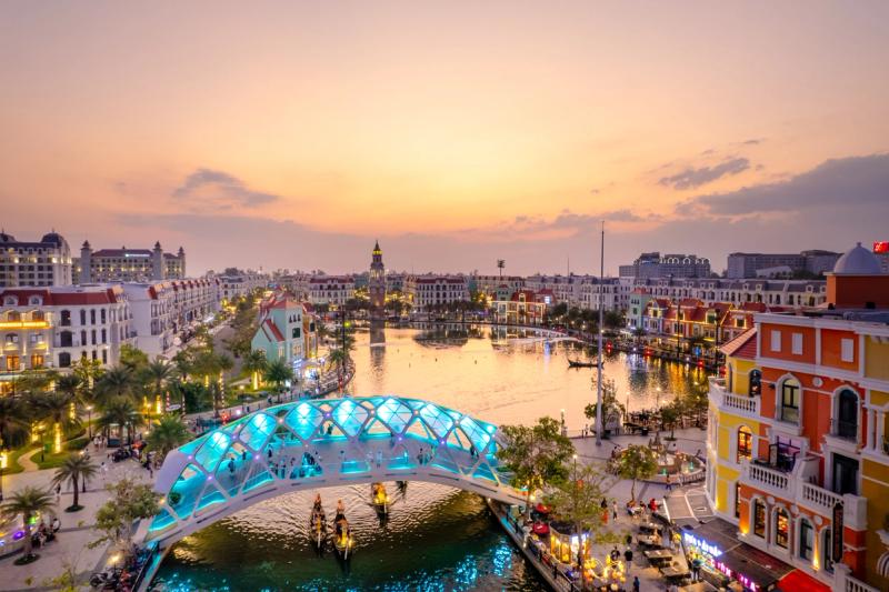 Grand World’s canal and illuminated bridge at dusk. This is the canal district, separate from the Quintessence cultural courtyard.