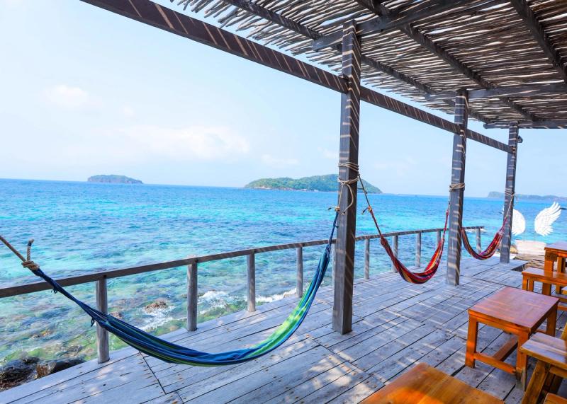 Hammocks and wooden seating on a covered platform beside the sea at May Rut Trong