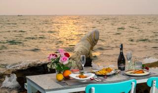 A seaside dining table set with flowers and wine