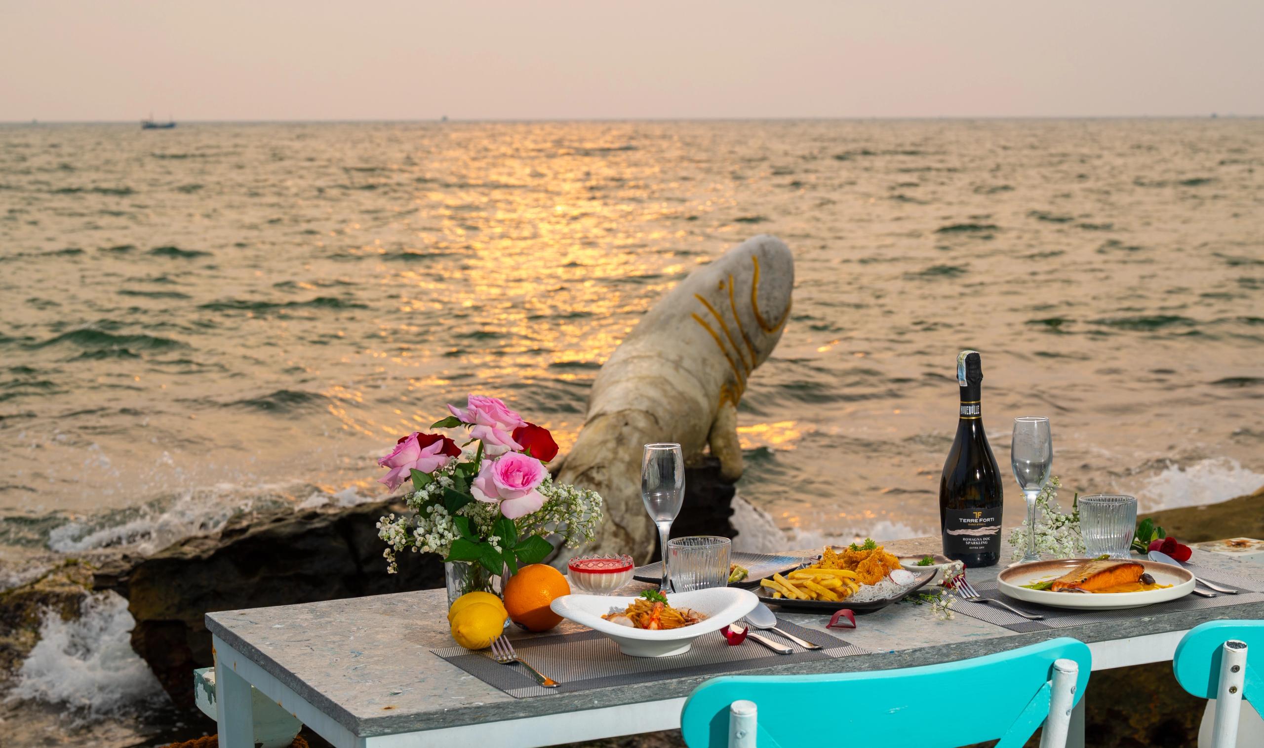 A seaside dining table set with flowers and wine