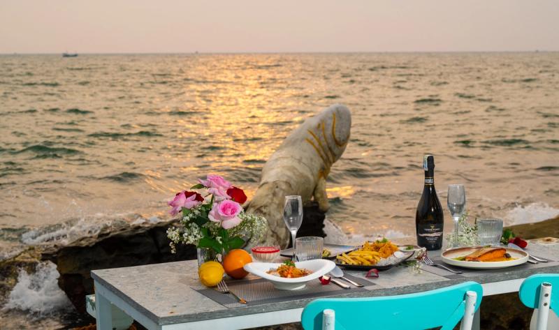 A seaside dining table set with flowers and wine