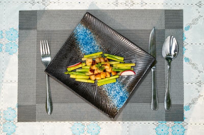Asparagus and browned pieces on a square blue-and-black plate