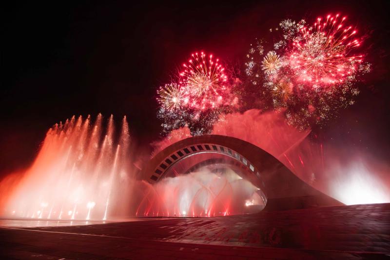 Fireworks above the curved Kiss of the Sea theatre in Sunset Town, on the southern waterfront. An archived performance photograph.