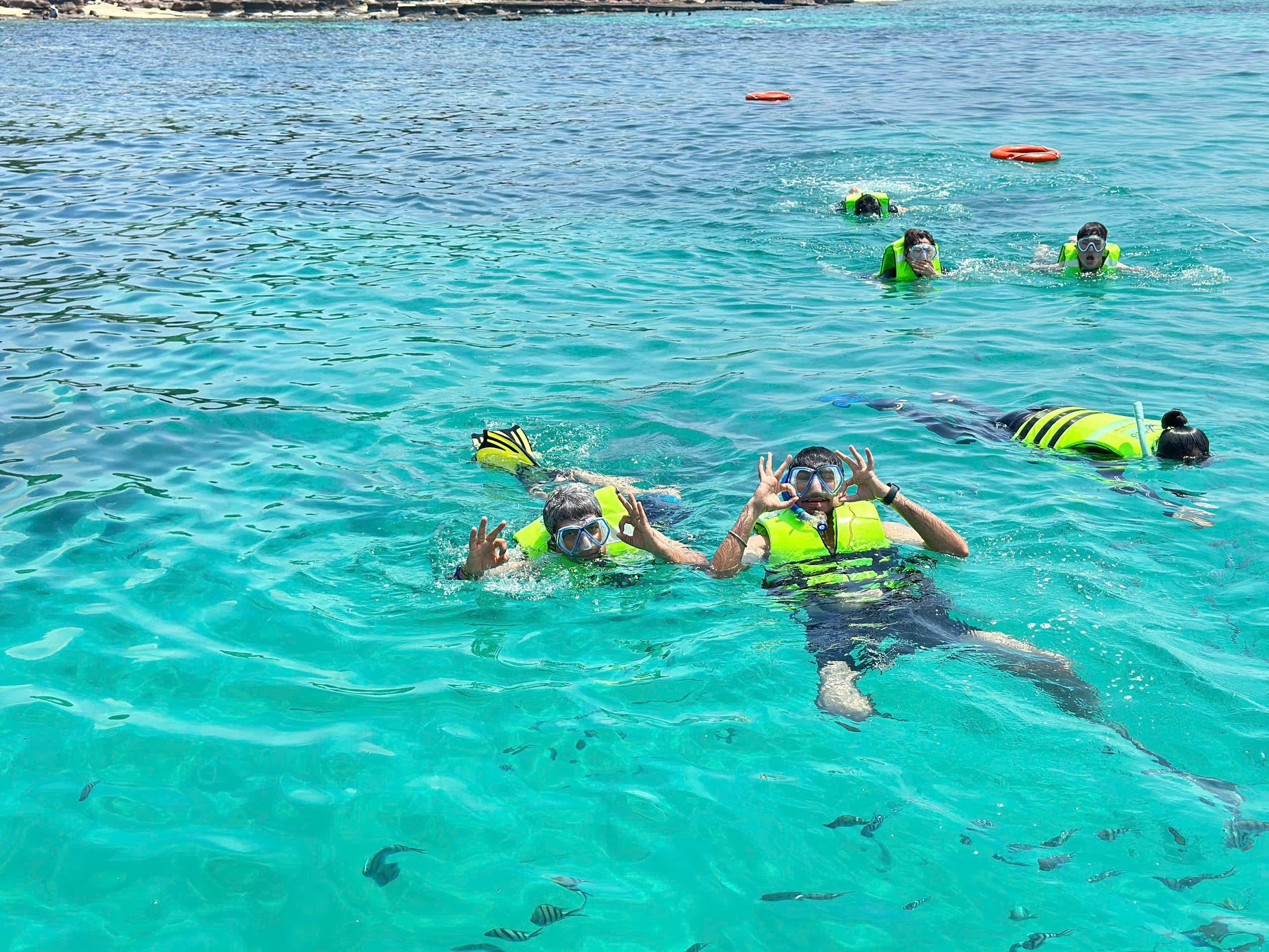 Snorkelers wearing bright flotation vests at the sea surface