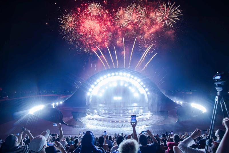 Audience members watching fireworks above the Kiss of the Sea stage