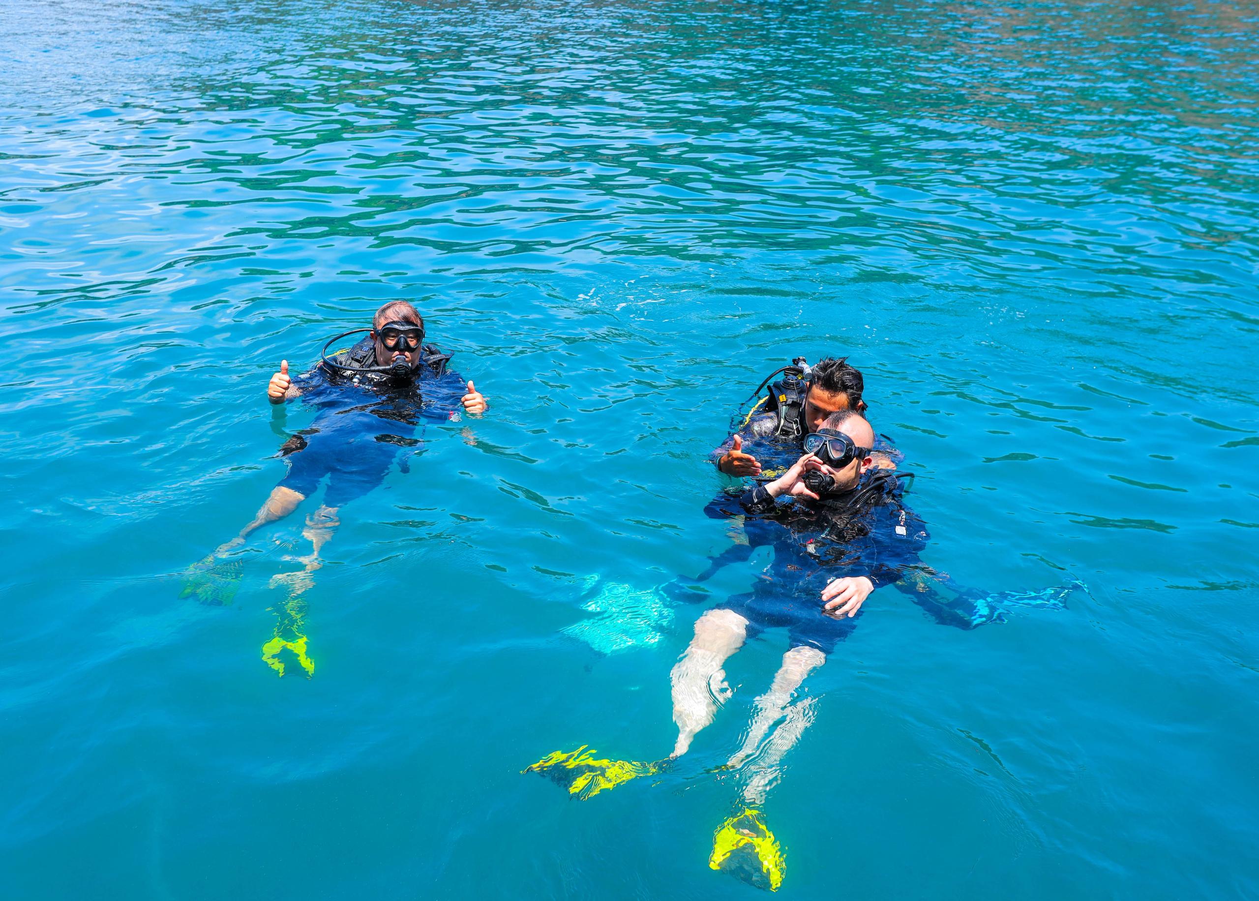 Divers with masks, fins and scuba equipment at the sea surface