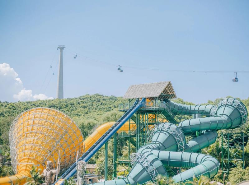 Water slides with a cable-car tower behind the trees