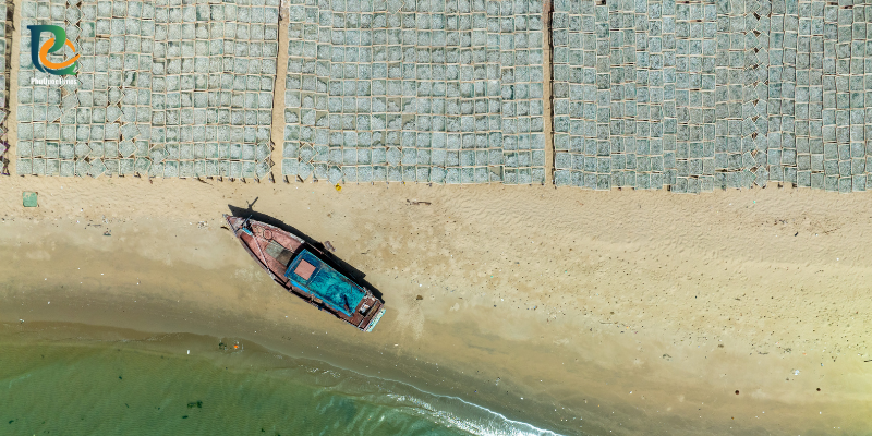 A fishing boat beside seafood drying racks on the Ham Ninh shore