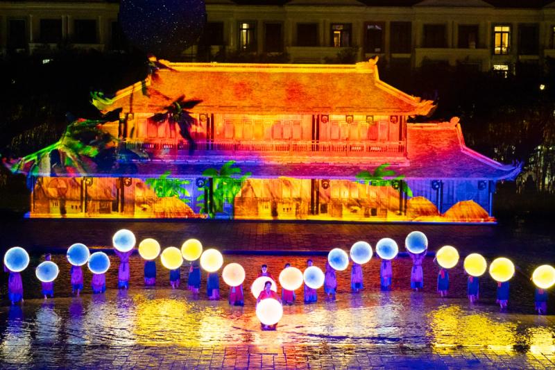 Performers holding illuminated round props on a reflective stage