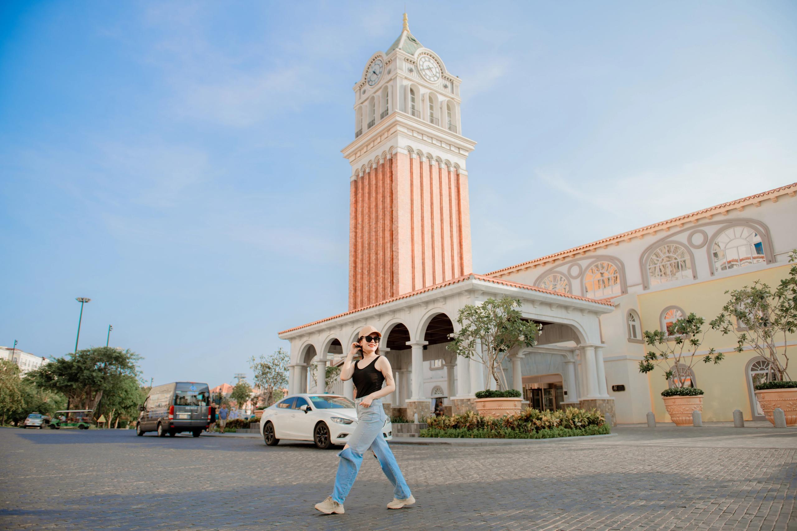 A visitor walking across the paved street beside Sunset Town’s clock tower