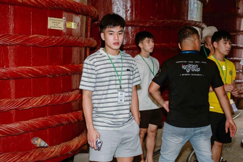 Visitors standing beside rope-bound wooden barrels