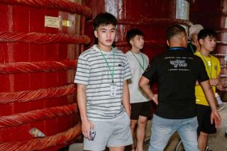 Visitors beside large wooden fish-sauce barrels