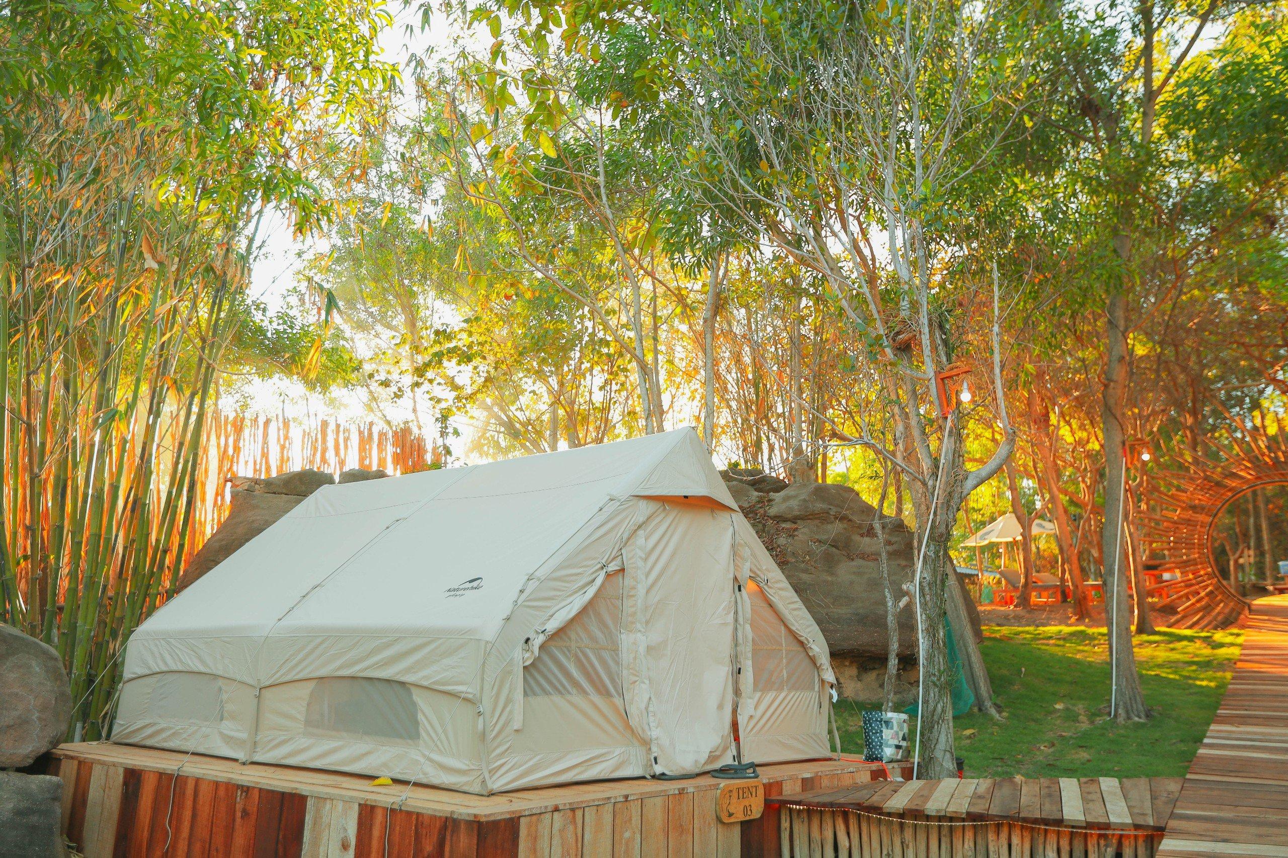 A canvas tent beside bamboo and a stone path