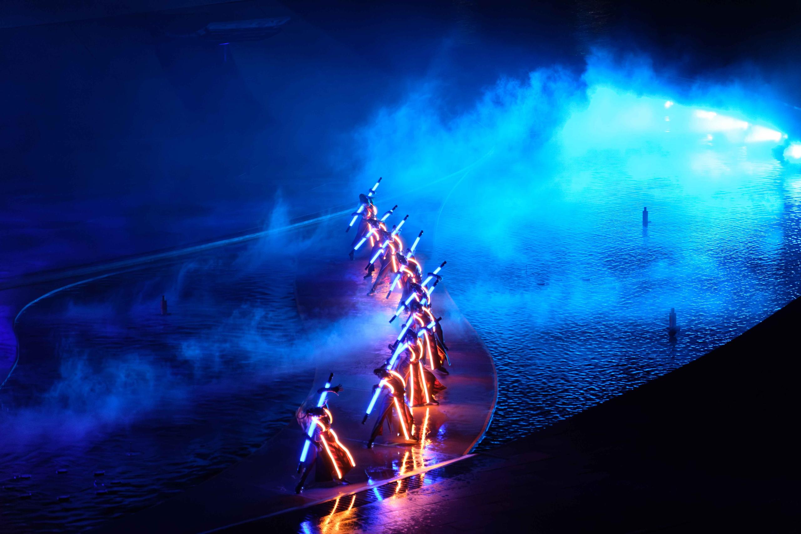 A line of performers on the blue-lit Kiss of the Sea stage