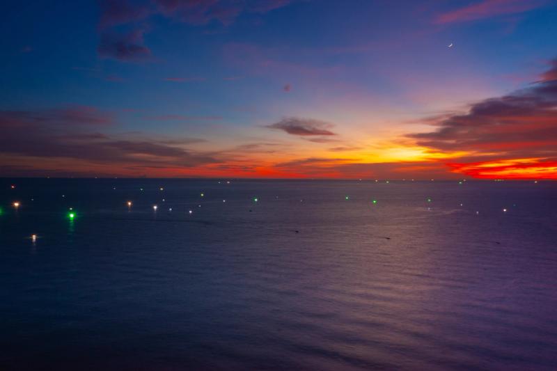 Small lights offshore beneath a colourful sunset