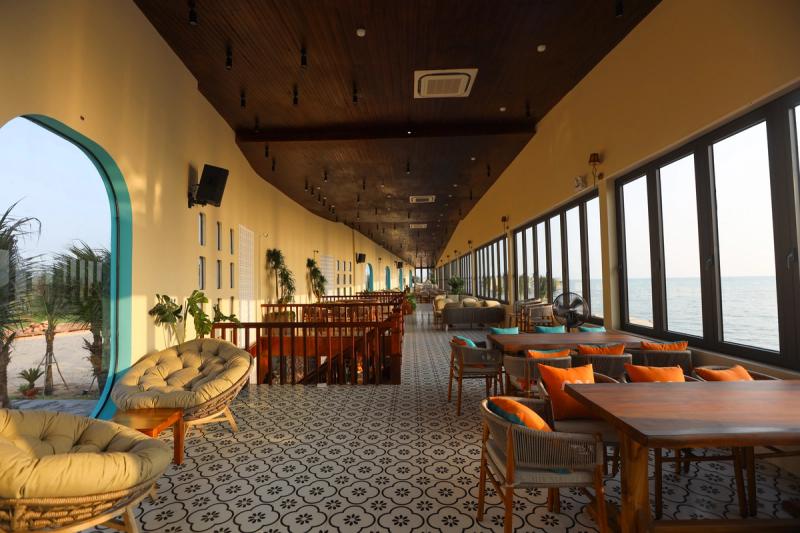 Indoor tables and cushioned chairs beside sea-facing windows