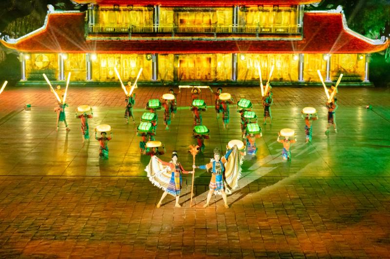 Dancers arranged in the courtyard beneath the red and gold Quintessence of Vietnam gateway