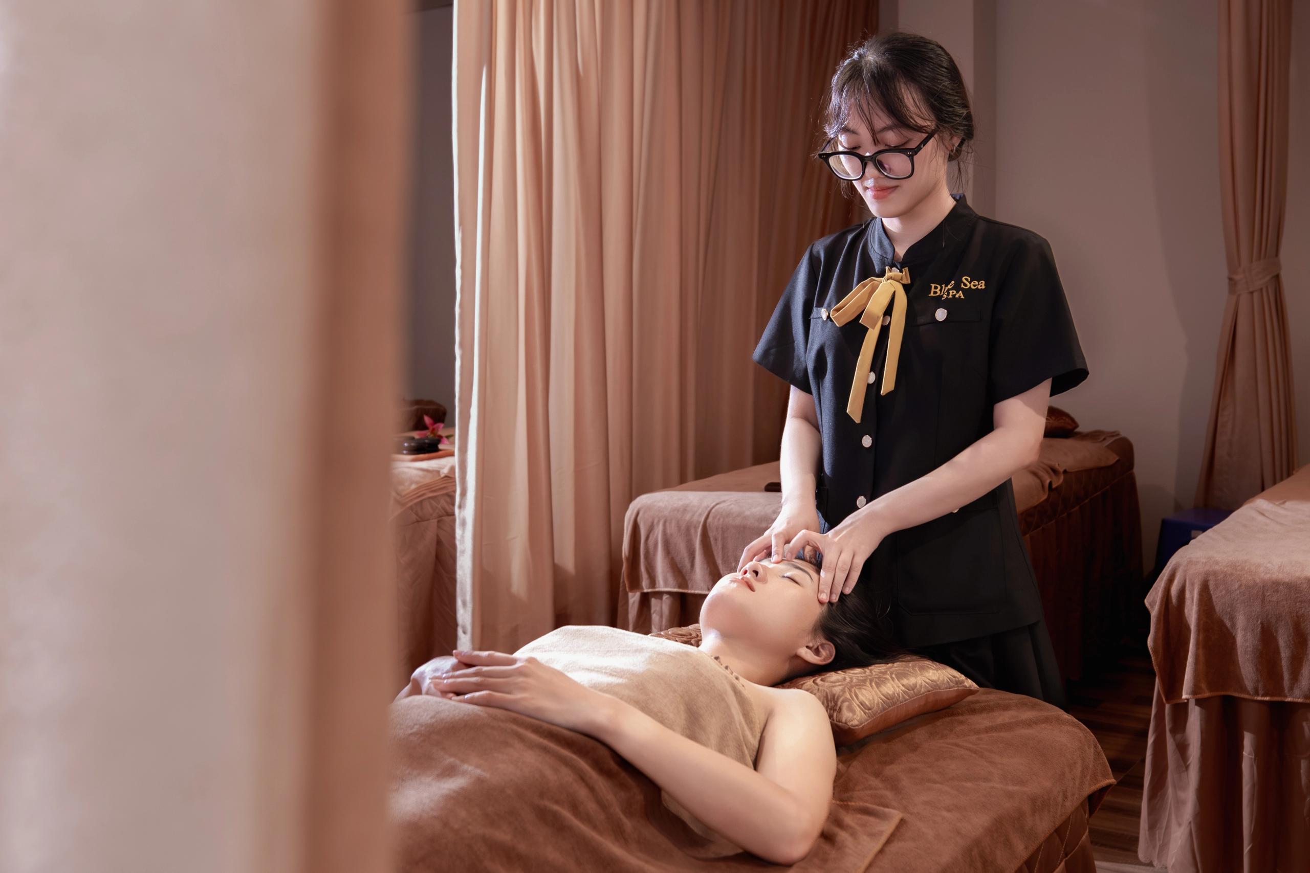 A therapist massaging a guest’s temples in a curtained room