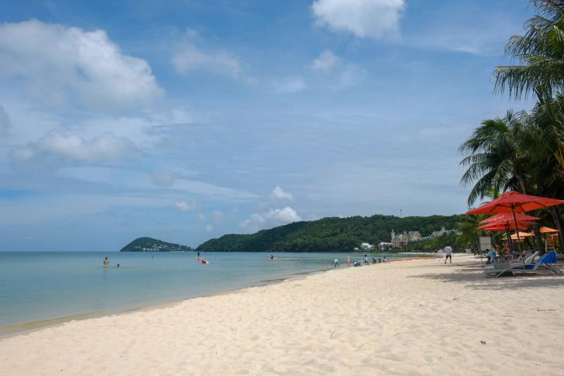 Khem Beach with calm water, visitors and red beach umbrellas