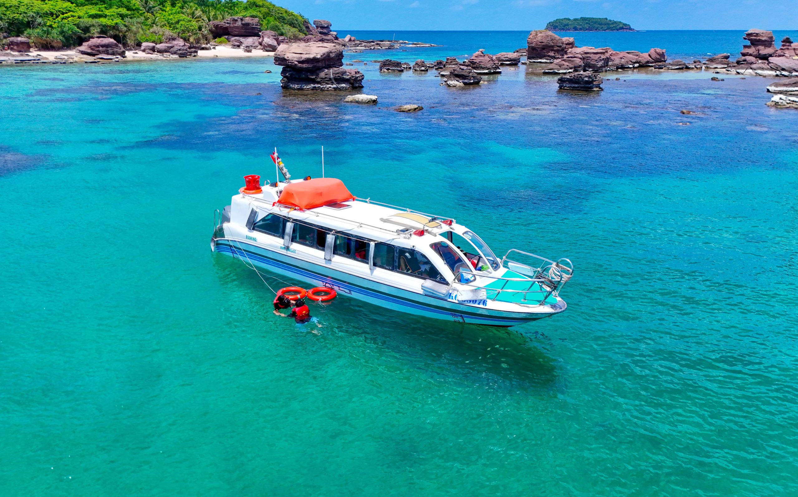 A speedboat beside a rocky island in turquoise water