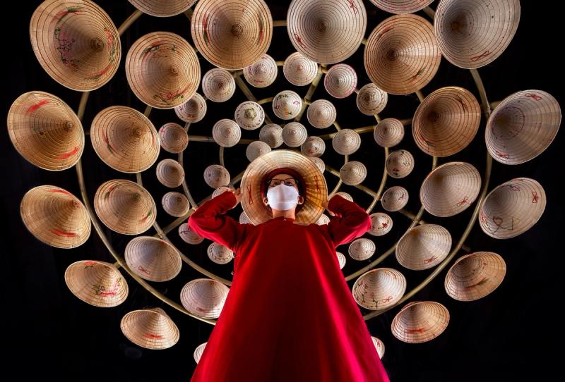 A visitor facing a wall display of conical hats