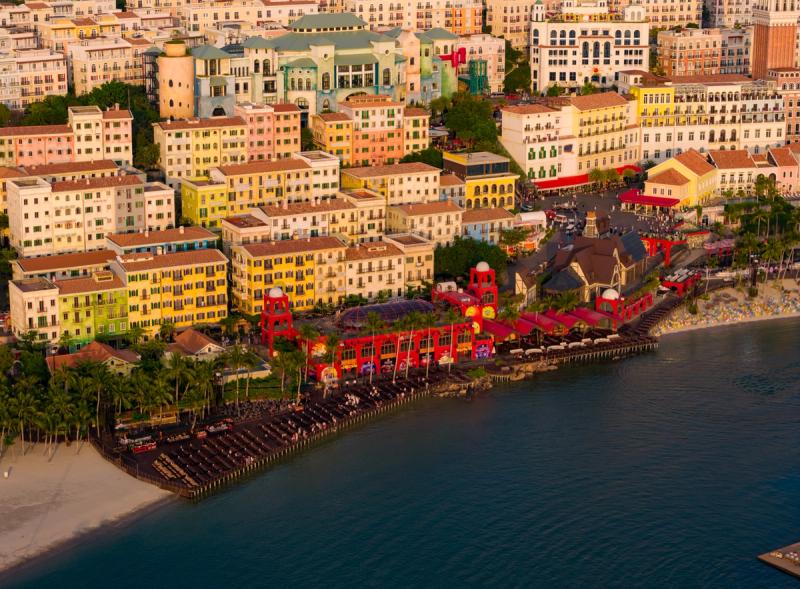 The red Sun Bavaria waterfront building beneath the terraced buildings of Sunset Town