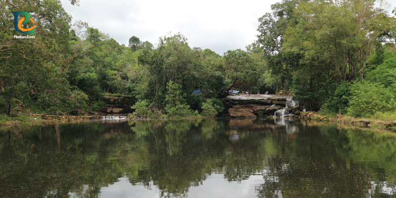 A still pool and flat rocks framed by forest at Da Ban Stream
