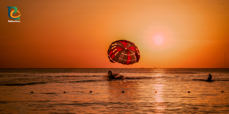 A parasail and boats silhouetted against sunset off Long Beach