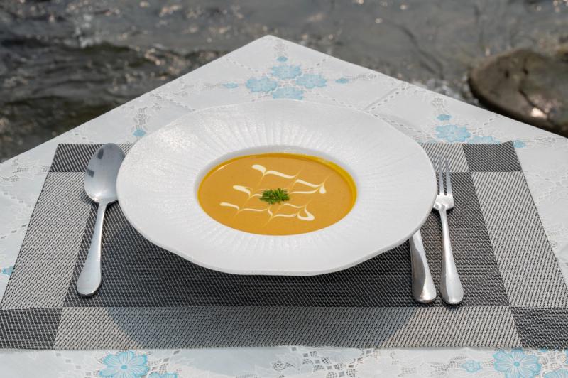 Orange soup with a white decorative swirl in a wide-rimmed bowl