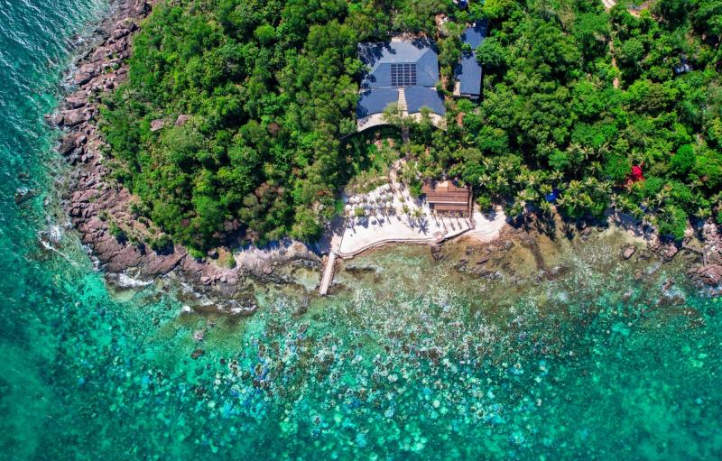 Overhead view of rocky shoreline, trees and shallow water at Hon Xuong