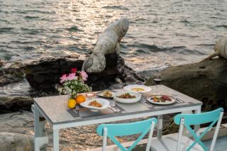 A table set with dishes beside a rocky shoreline