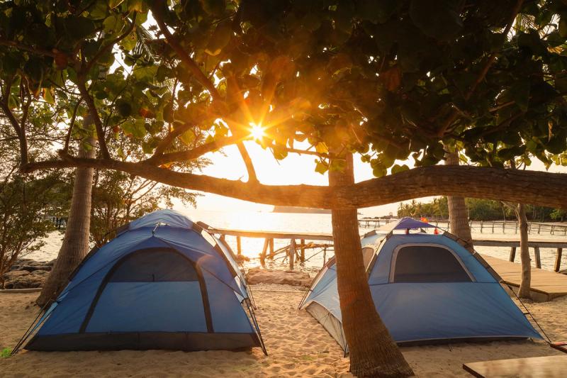 Blue tents beside the shoreline at sunset