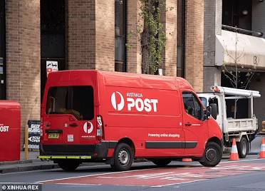A red Australia Post delivery van parked on a city street.