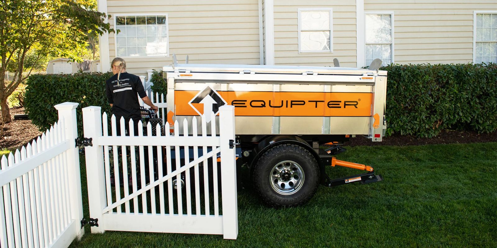 Equipter 4000 driving through an open vinyl fence gate into a backyard