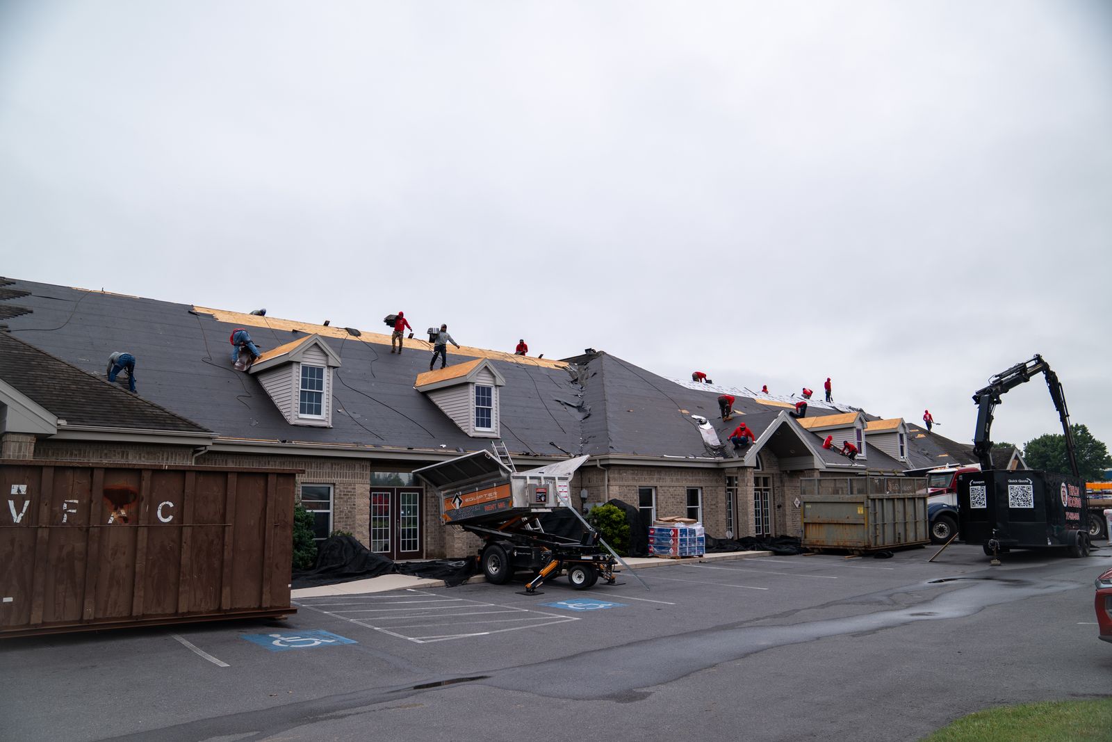 Wide view of a multi-home re-roof with an Equipter 4000 raised at a house and dumpsters on site