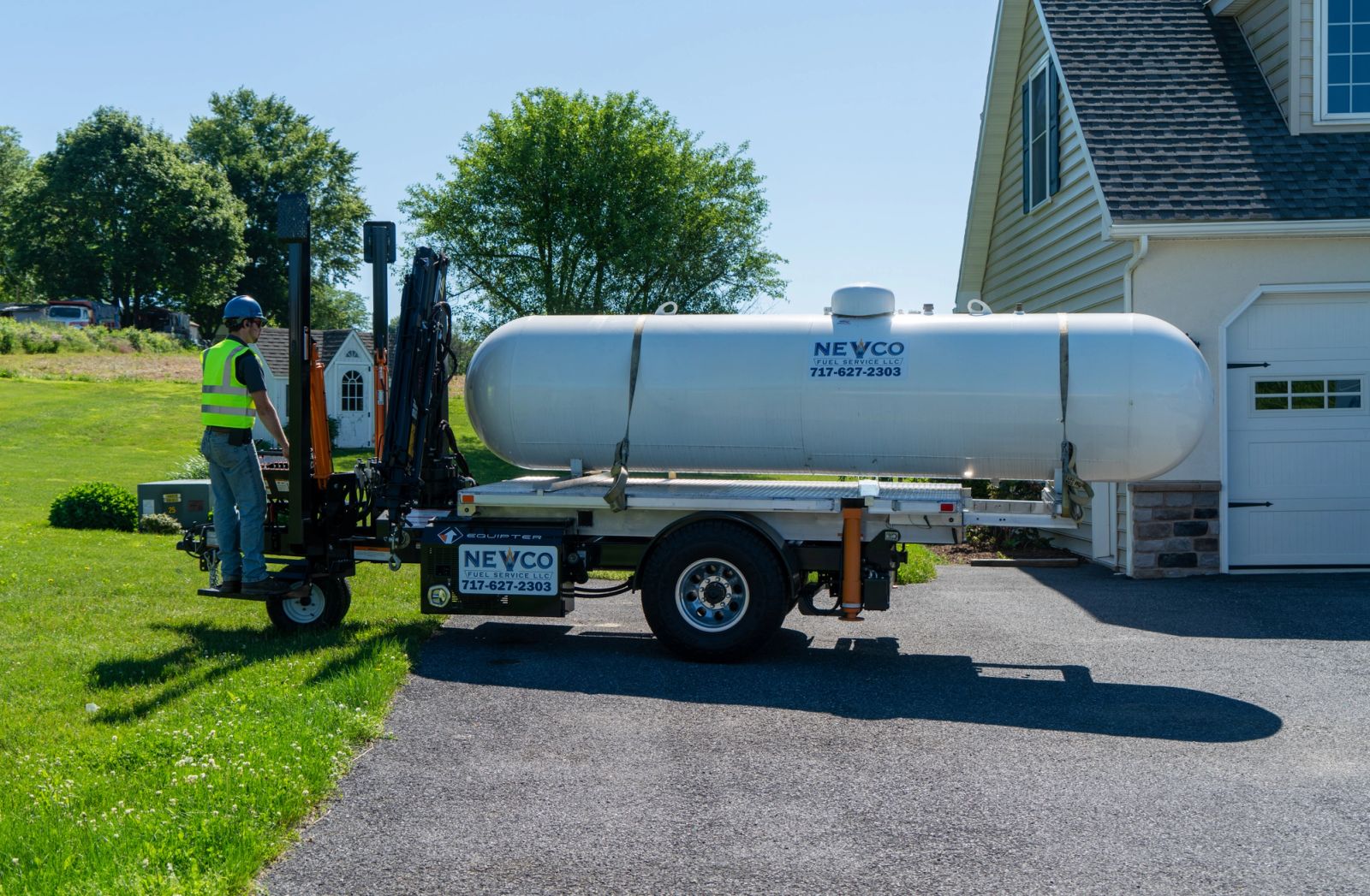 Equipter 5400 carrying a large tank on a residential driveway beside a house