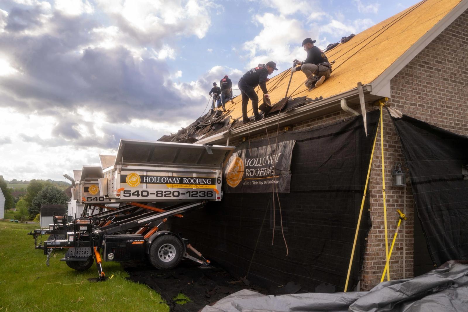 Wide view of a roofing crew tearing off above a raised Equipter 4000 under big clouds.