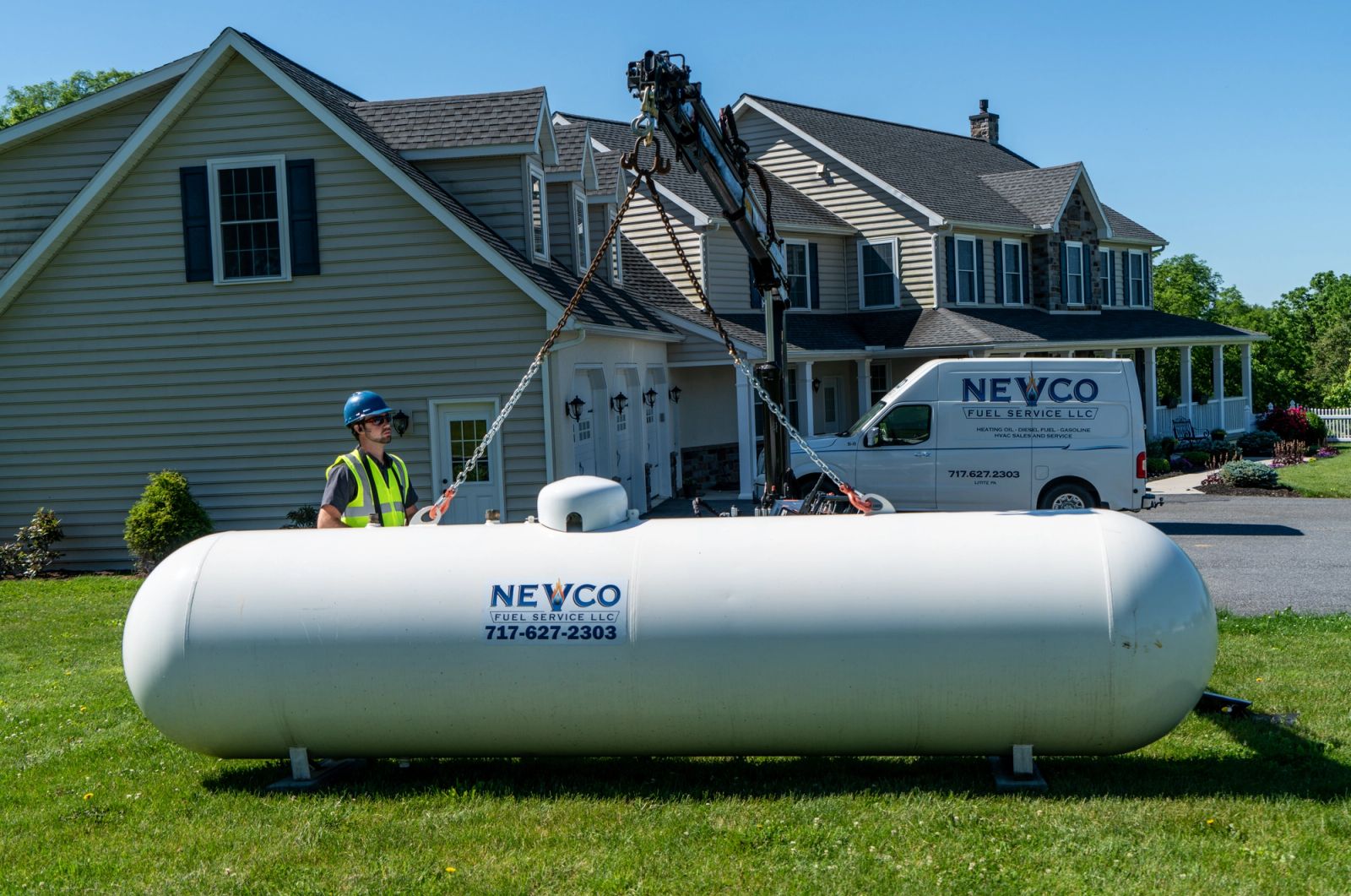 Equipter 5400 crane placing a large propane tank on the lawn beside a house