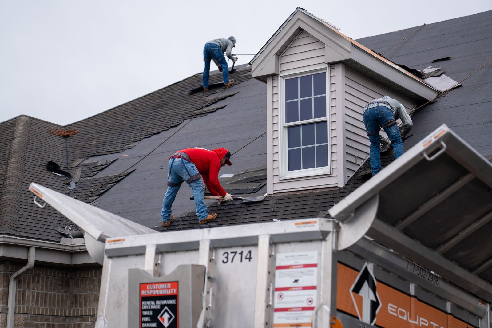 Roofers stripping shingles directly into an Equipter 4000 container