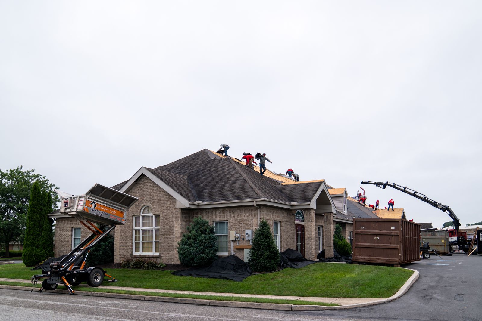 Equipter 4000 raised beside a house during a re-roof, with a dumpster parked at the curb