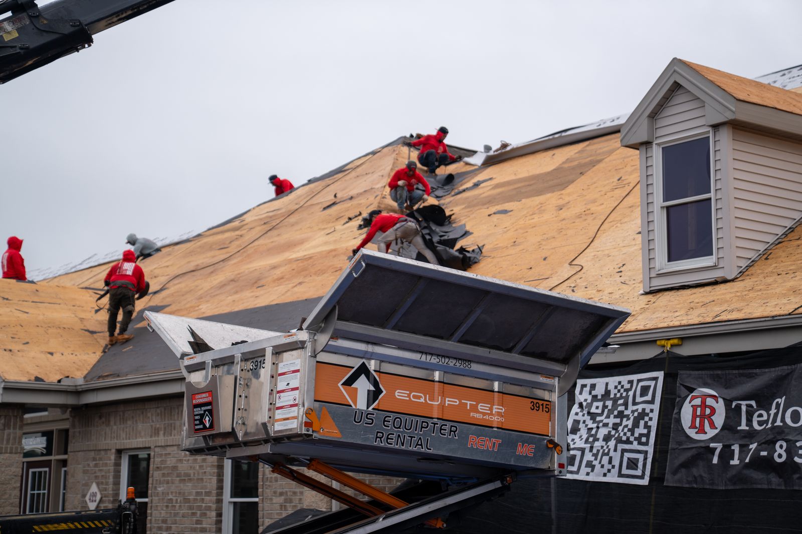 Roofing crew tearing off shingles straight into a raised Equipter 4000
