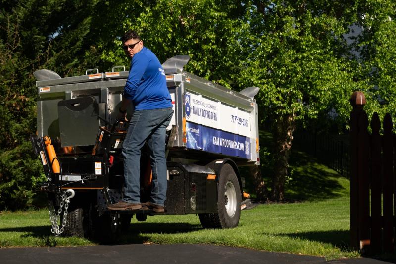 A roofer driving the self-propelled Equipter 4000 down a residential driveway.