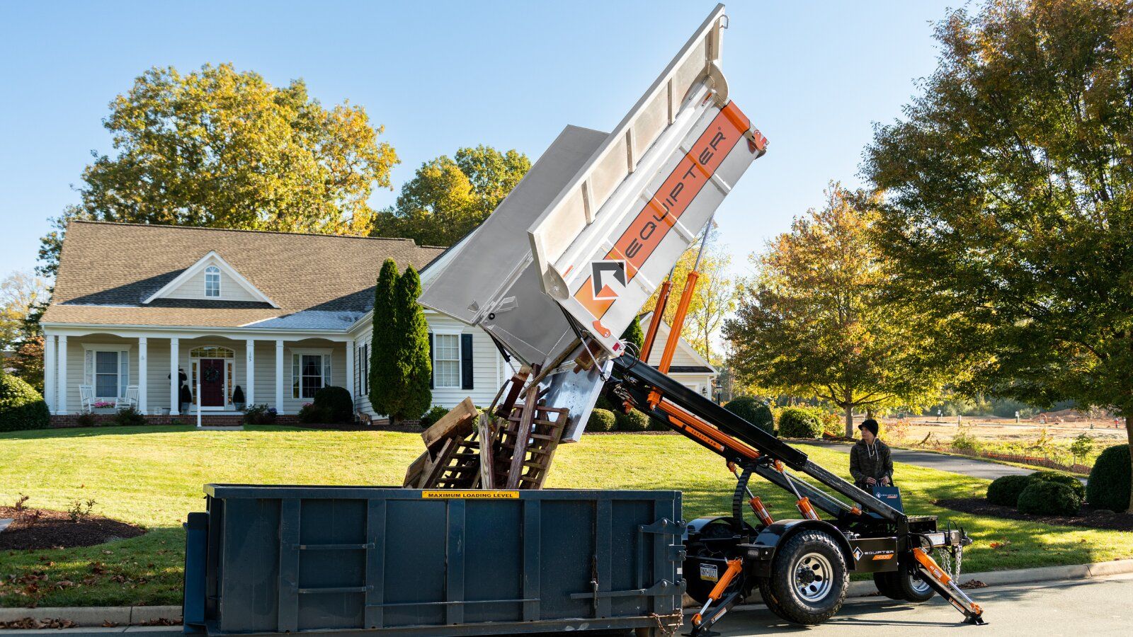 Equipter 4000 lifting and emptying its container into a roll-off dumpster