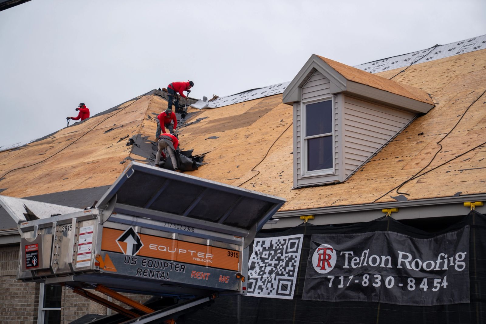 Equipter 4000 raised to the eave beside a dormer while roofers strip the roof