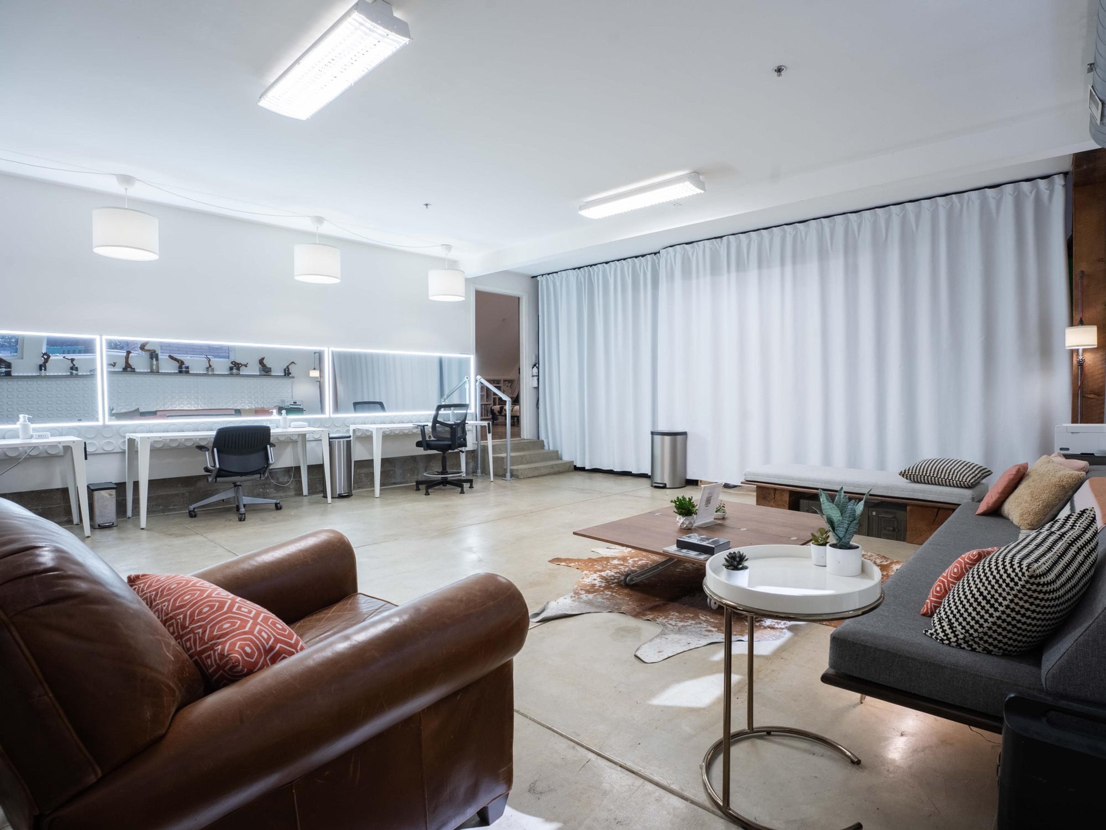 Production floor with desks along the curtain wall and a lounge beyond