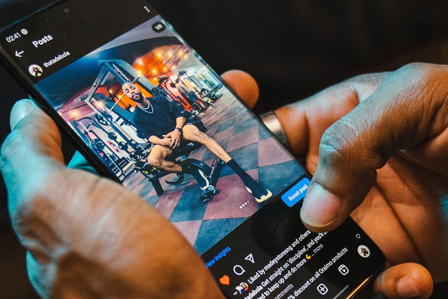 Hands holding a phone showing an Instagram post with a Boost Post button