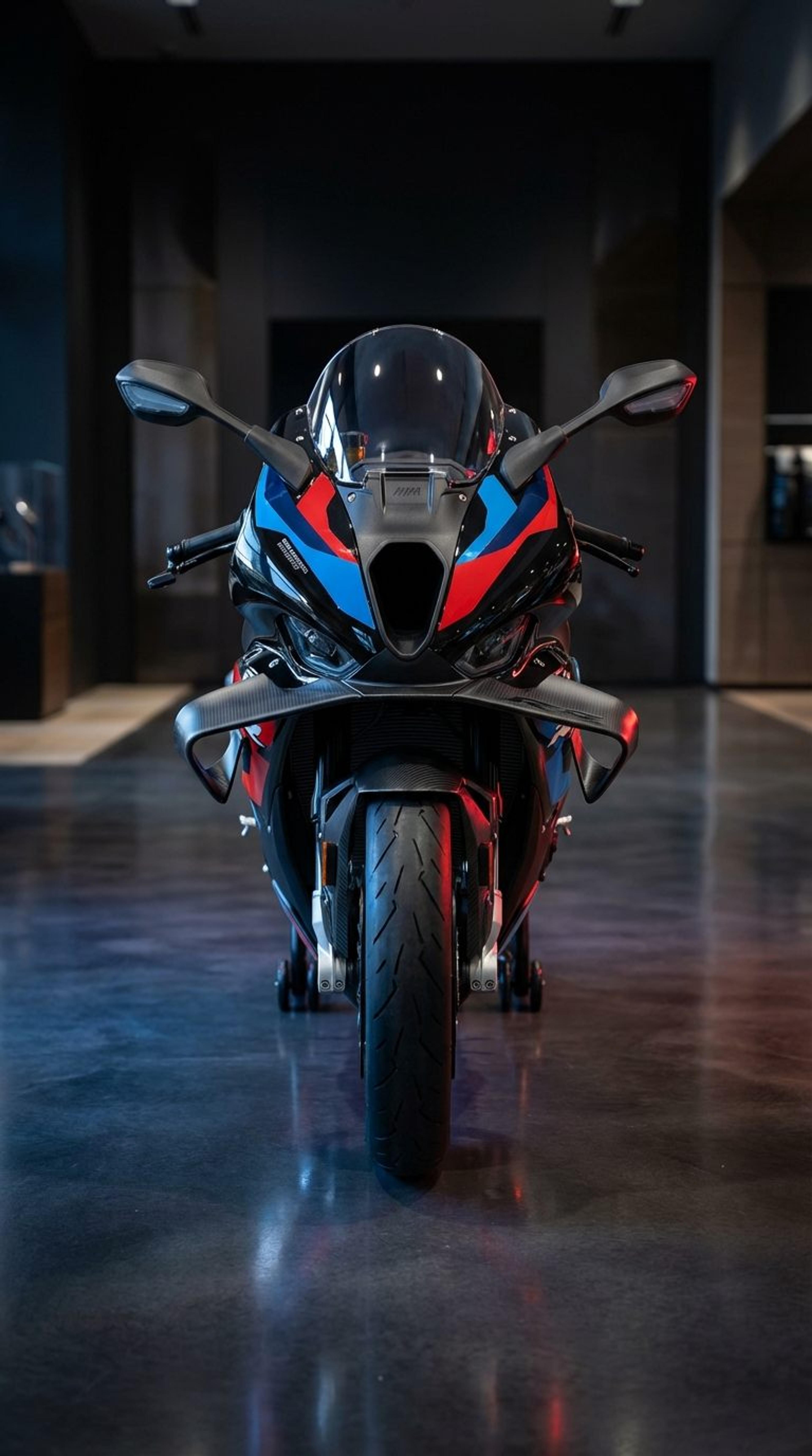 BMW M1000RR sportbike lit head-on in a dark showroom